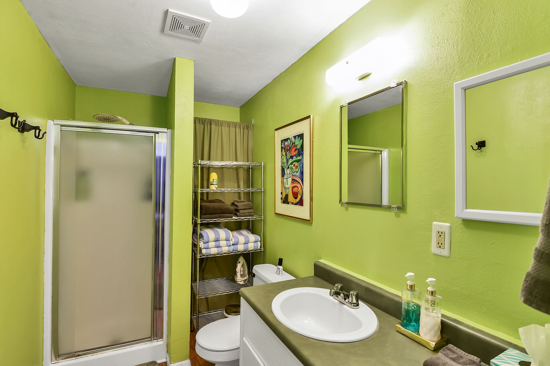A bathroom with a shower, toilet, sink, and a mirror.