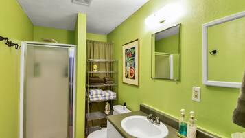 A bathroom with a shower, toilet, sink, and a mirror.