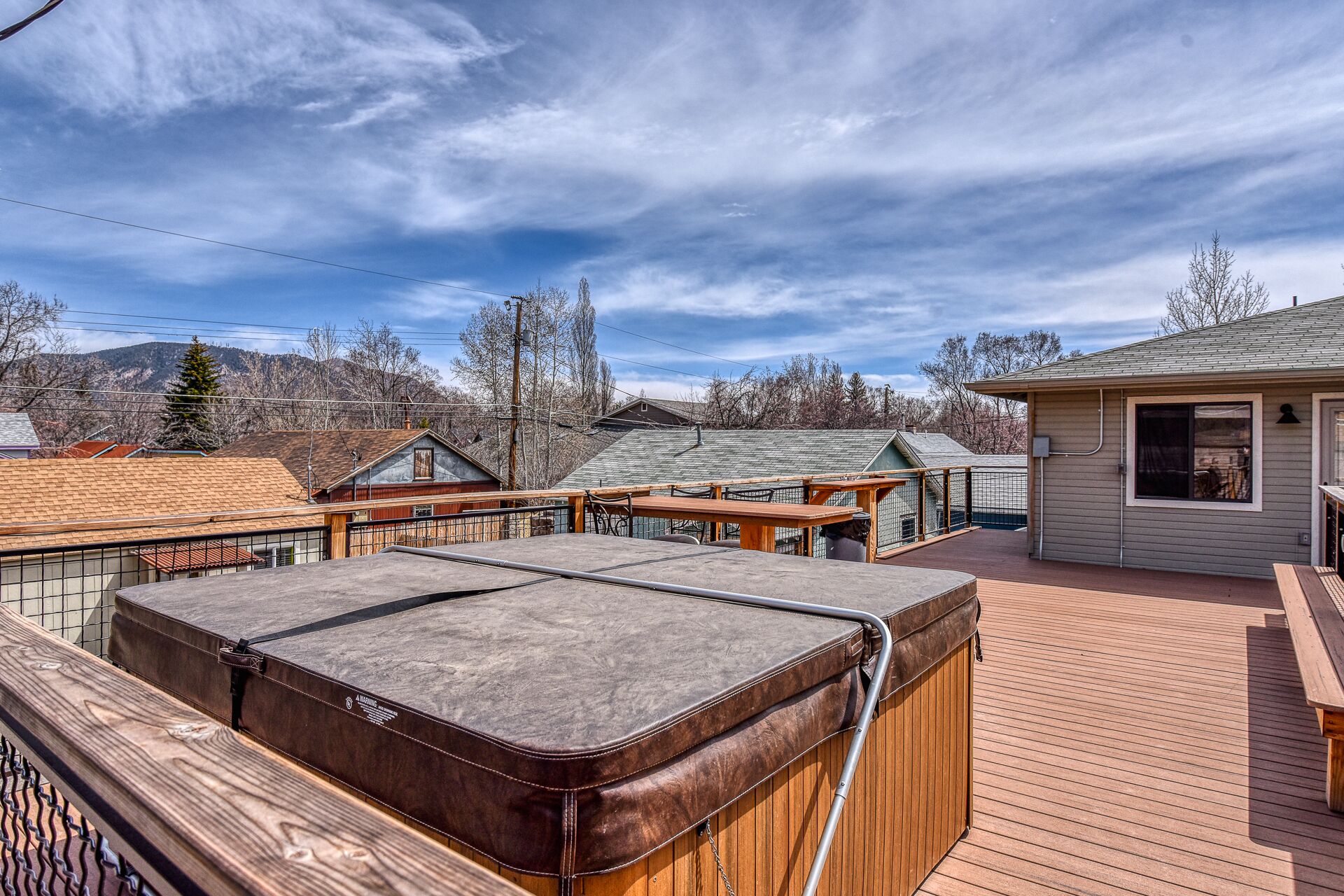 Terraza en la azotea con jacuzzi, cubierta de madera y un pequeño edificio con ventanal.