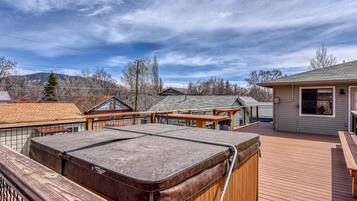 Terraza en la azotea con jacuzzi, cubierta de madera y un pequeño edificio con ventanal.