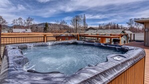Een hottub op een houten terras met uitzicht op huizen en bomen.