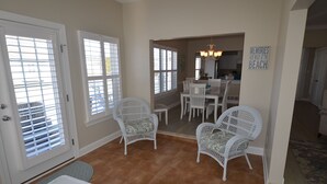 A dining area with white wicker chairs and a table, a kitchen in the background, and a sign on the wall that reads "MEMORIES ARE MADE AT THE BEACH". - Less than 2 miles to the beach and boardwalk! (Rehoboth Beach)