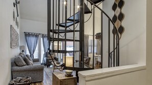Una sala moderna con un sofá, sillas, una mesa de centro y una escalera de diseño único.