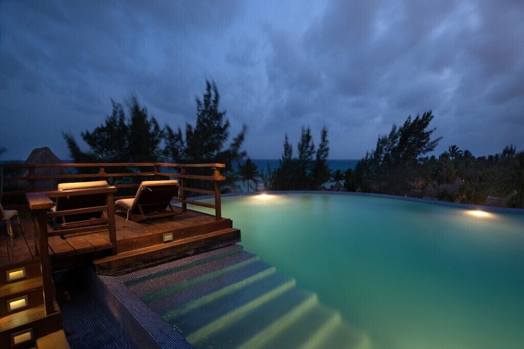 A poolside area with wooden deck seating and steps leading into the pool.