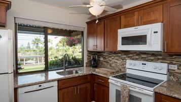 A kitchen with wooden cabinets, a microwave, a stove, and a dishwasher.