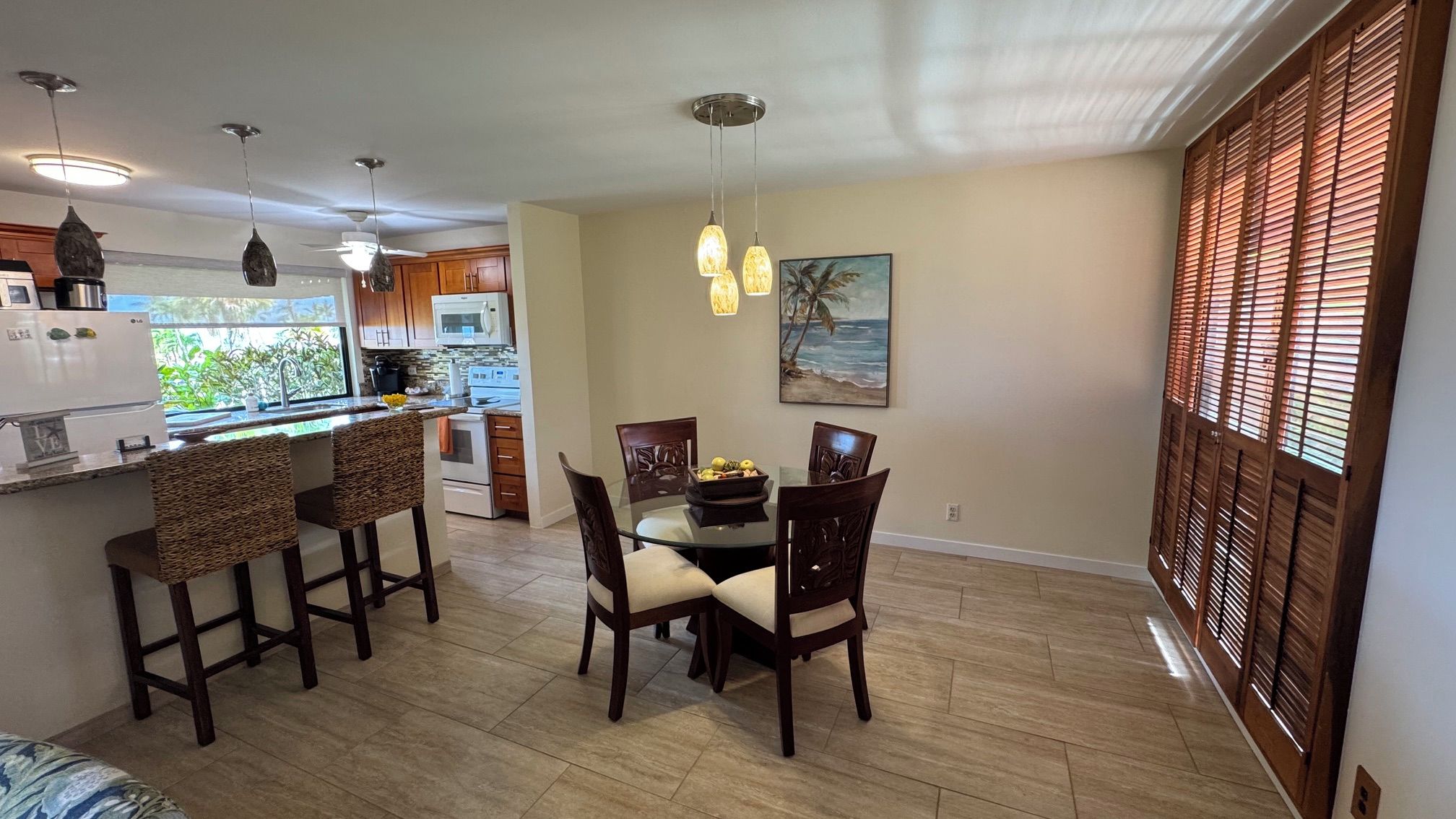 A modern kitchen with a dining area, wooden chairs, and a painting on the wall.