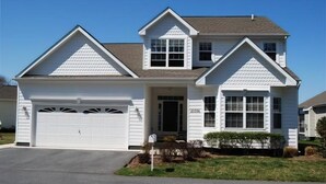 A two-story house with a garage, a front porch, and a small front yard. - Less than 2 miles to the beach and boardwalk! (Rehoboth Beach)
