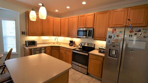 A modern kitchen with wooden cabinets, stainless steel appliances, and pendant lighting. - Less than 2 miles to the beach and boardwalk! (Rehoboth Beach)