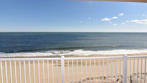 A beach view from a balcony with a white railing.