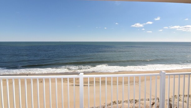 A beach view from a balcony with a white railing.