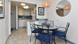 A compact kitchen with white cabinets, a built-in dishwasher, and a small island with a sink.