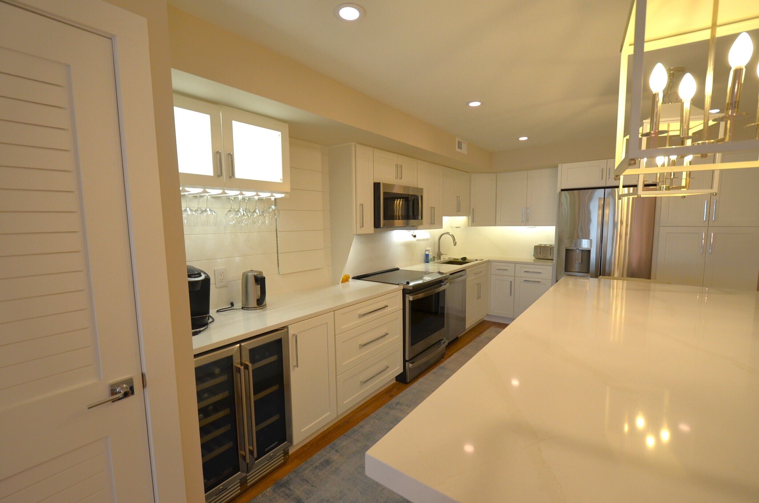 A modern kitchen with white cabinetry, stainless steel appliances, and a large island.