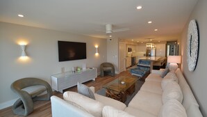Una sala de estar moderna con un sofá, sillones, una mesa de centro y un televisor montado en la pared.
