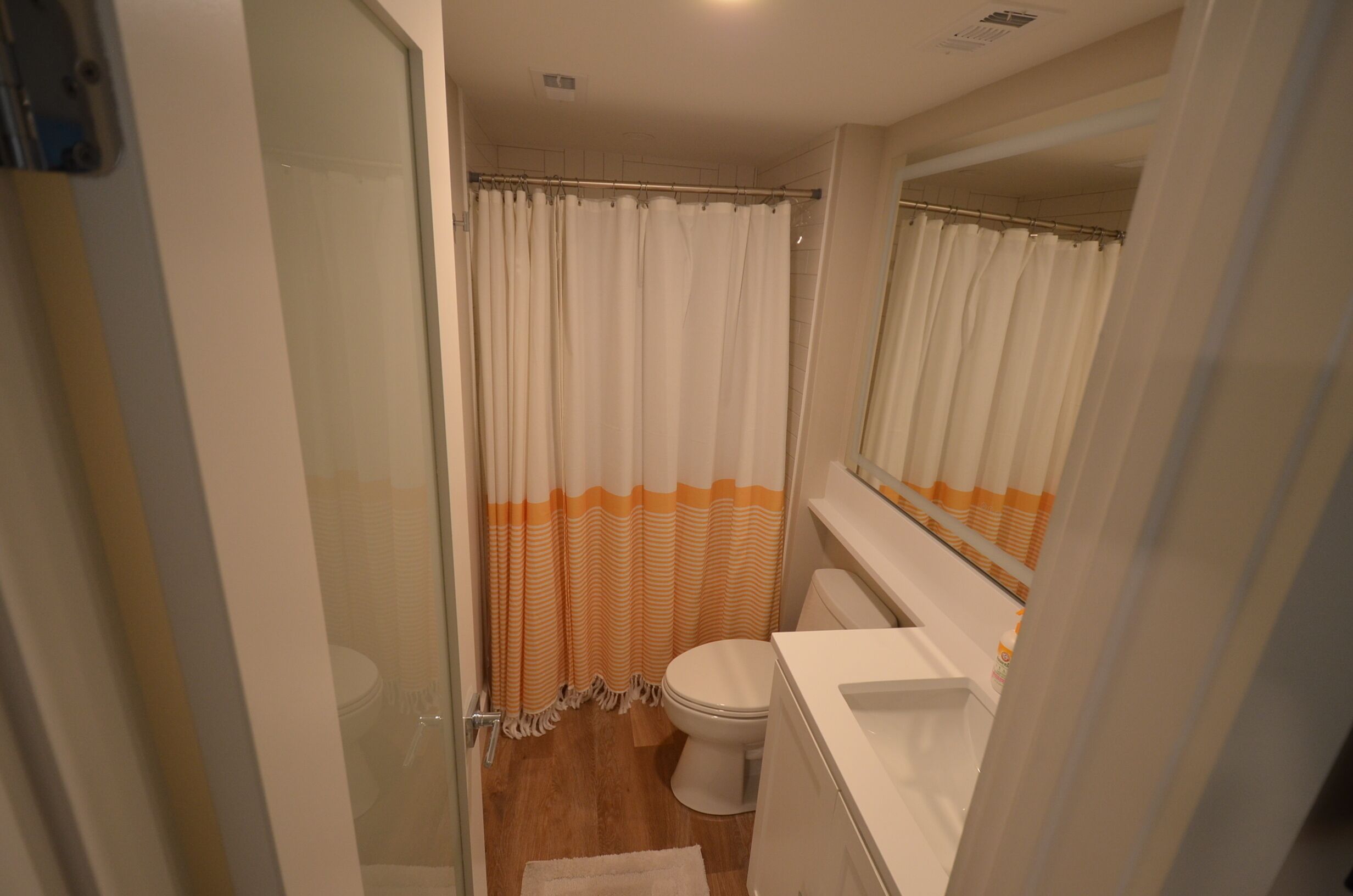 A bathroom with a glass shower enclosure, a toilet, and a white sink.