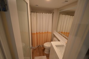 Een badkamer met een douchecabine van glas, een toilet en een wit wastafel.