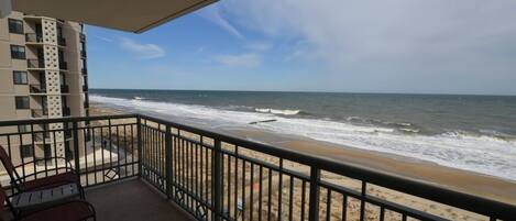 A balcony with a view of the beach and ocean.