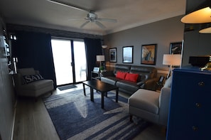 A living room with a sofa, armchair, coffee table, and a blue cabinet.