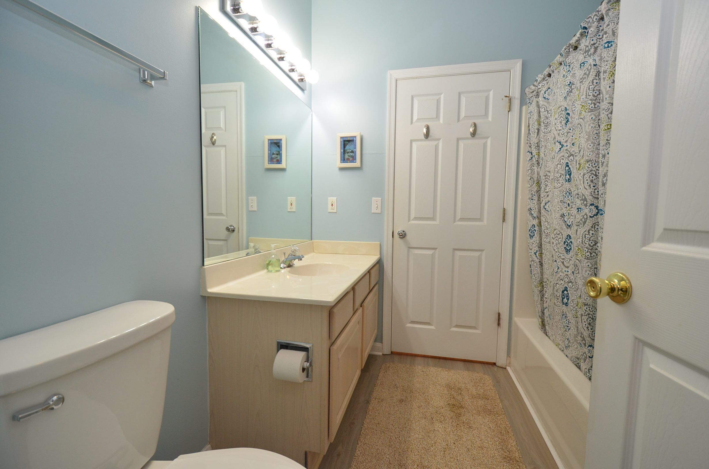 A bathroom with a toilet, sink, mirror, and door.