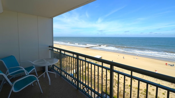 A balcony with a view of a beach, a table, and two chairs. - Edgewater House - Ocean Front Units With Spectacular Views! (Rehoboth Beach)