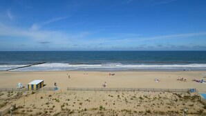 A beach with a sandy shore, a few people, and a clear blue sky. - Edgewater House - Ocean Front Units With Spectacular Views! (Rehoboth Beach)