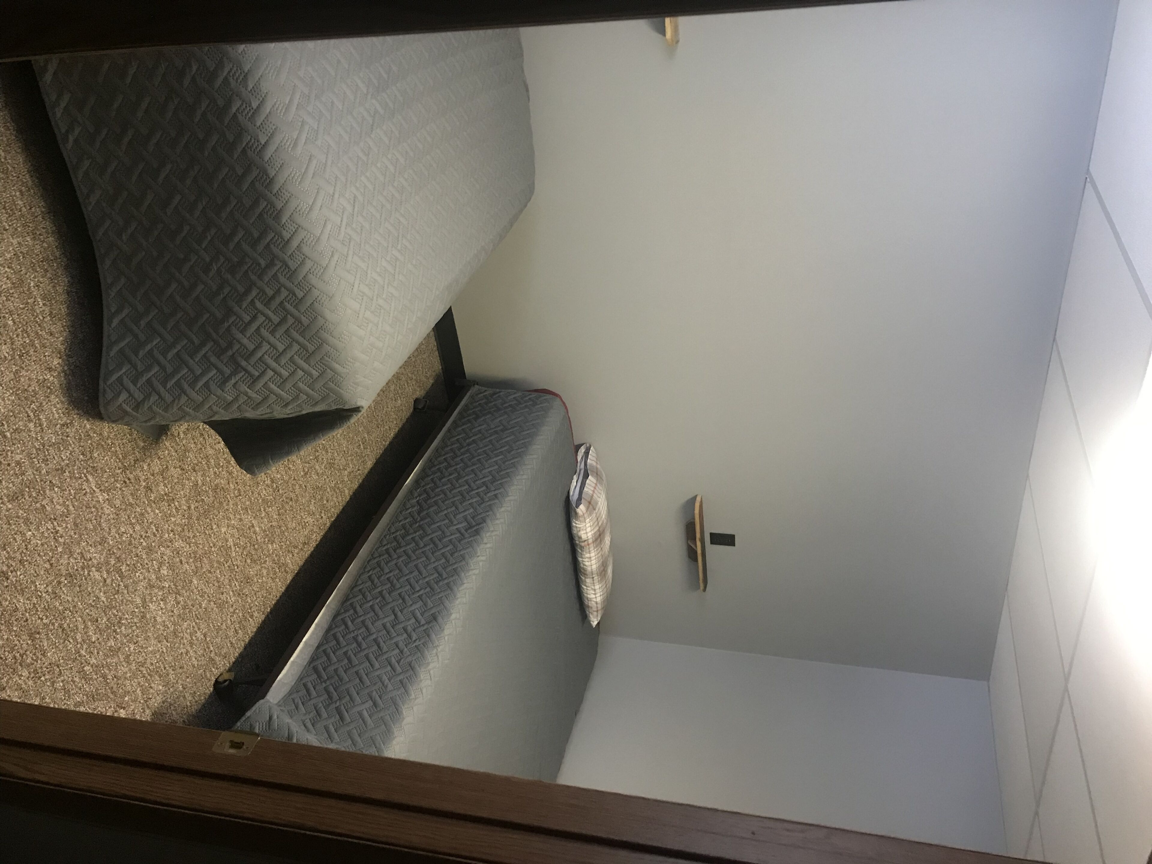 Een compacte kamer met een bed, een klein nachtkastje en een wandlamp.