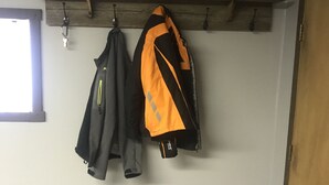 Une pièce avec un banc en bois adossé au mur, sur lequel sont posées plusieurs vestes.
