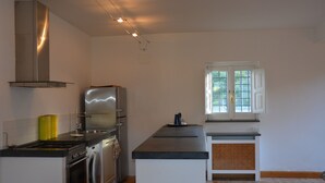 A modern kitchen with stainless steel appliances, a built-in oven, and a large window with white shutters. - Villa Nocellara (Castiglione di Sicilia)
