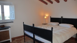 A bedroom with a bed, a bedside table, a lamp, and a window with open shutters. - Villa Nocellara (Castiglione di Sicilia)