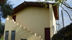 A building with a beige exterior, a red door, and a staircase leading to the entrance. - Villa Nocellara (Castiglione di Sicilia)