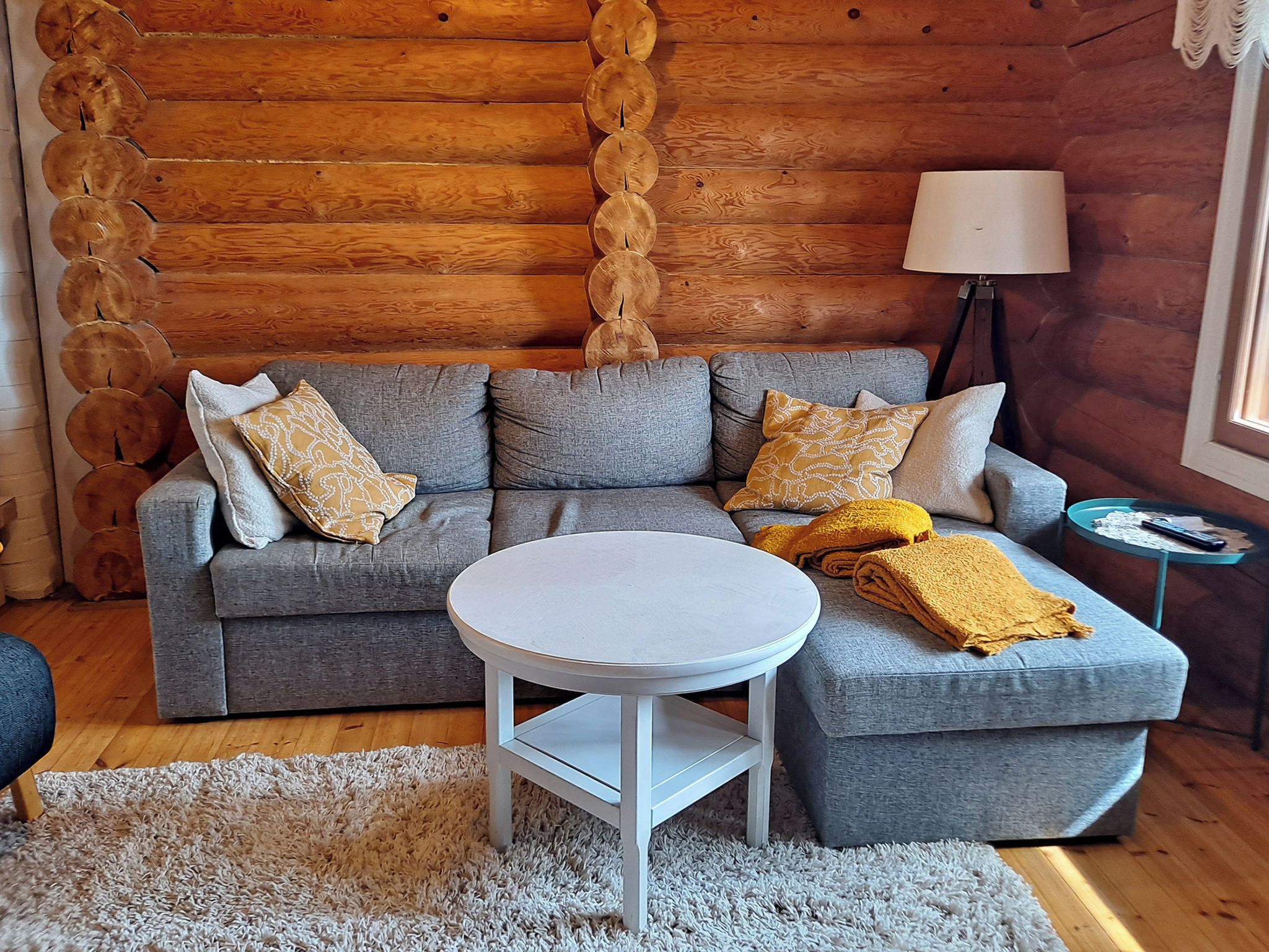 A cozy living room with a grey sofa, a round white table, and a lamp.
