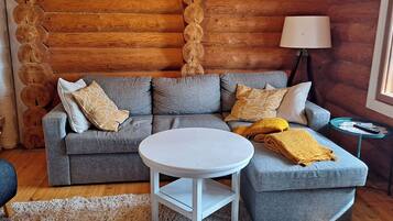 A cozy living room with a grey sofa, a round white table, and a lamp.