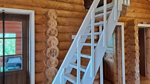 L'intérieur d'un chalet en bois, avec un escalier blanc menant à un niveau supérieur.