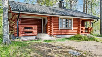 A log cabin with a front porch, a chimney, and a window.