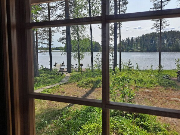 A view through a window of a lakeside property with a dock, chairs, and a path leading to the water. - Haapaniemi, cjoe020 by Interhome (Joensuu)