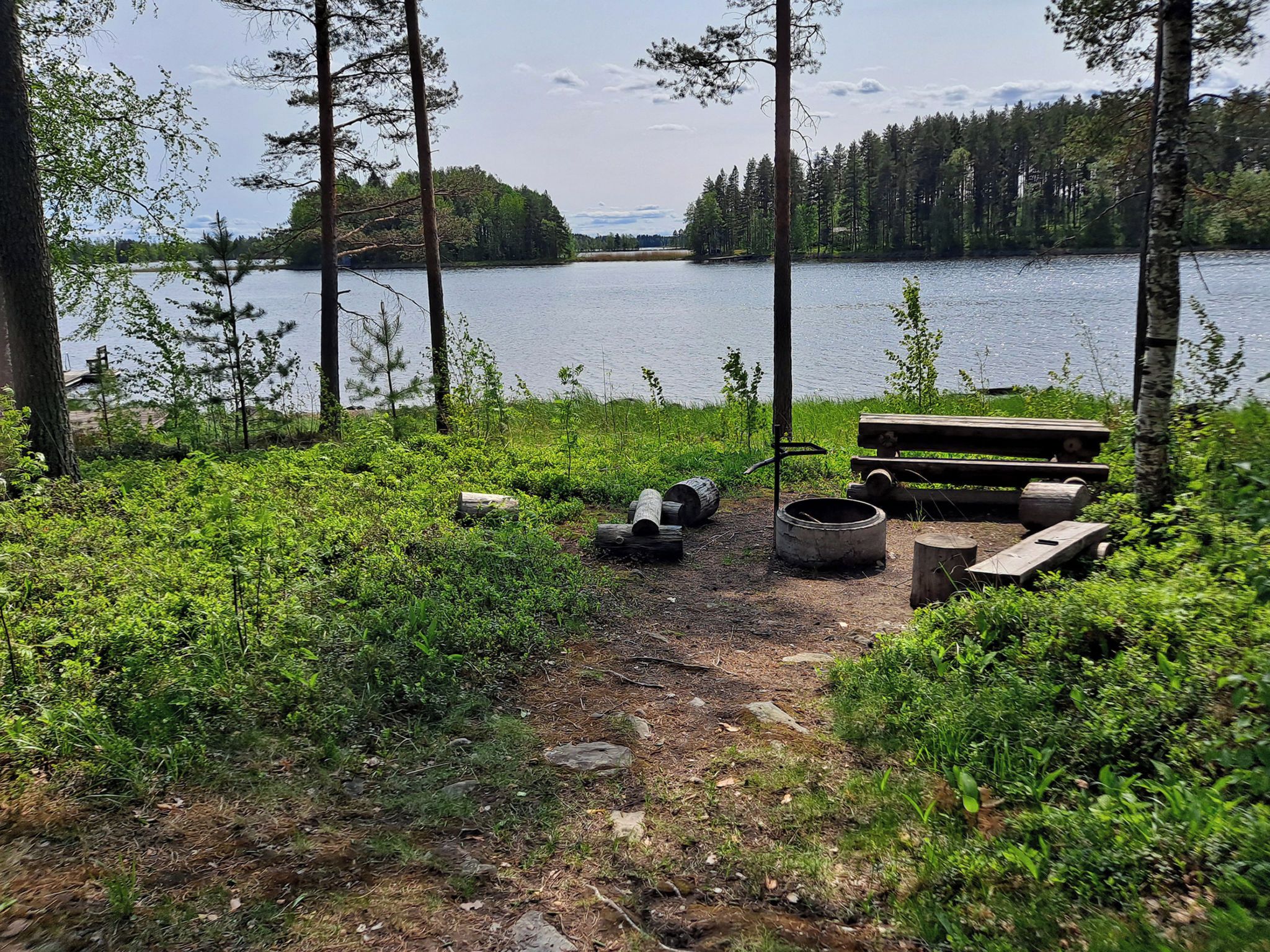 A lakeside campsite with a wooden bench and a fire pit.
