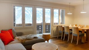 Una sala de estar acogedora con un sofá, una mesa redonda de madera y un comedor con sillas y una mesa.