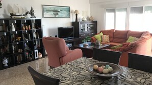 A living room with a sofa, armchairs, a coffee table, and a bookshelf filled with books and decorative items.