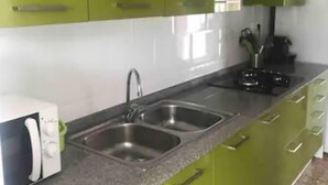 A kitchen with green cabinets, a double sink, and a microwave.