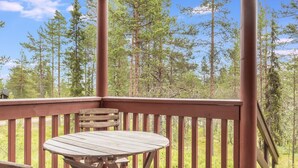 Eine Holzterrasse mit Tisch und Bank, mit Blick auf ein bewaldetes Gebiet.