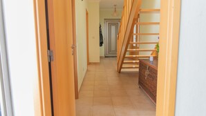 Un corridoio con porte in legno, una scala e un pavimento piastrellato.