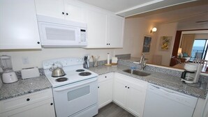 A compact kitchen with white cabinets, a microwave, a stove, a sink, and a coffee maker. - Edgewater House - Ocean Front Units With Spectacular Views! (Rehoboth Beach)