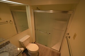 Une salle de bain comprenant des toilettes, une douche à parois de verre et un comptoir en granit.