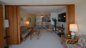 A living room with a sofa, armchair, coffee table, and a dining area with chairs and a table. - Edgewater House - Ocean Front Units With Spectacular Views! (Rehoboth Beach)