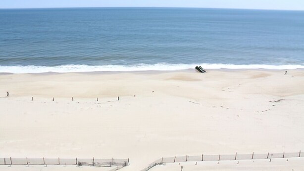 Ein Strand mit sandigem Ufer und freiem Blick auf den Ozean.