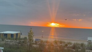 A beach with a sunset, a building, and a tree. - Edgewater House - Ocean Front Units With Spectacular Views! (Rehoboth Beach)
