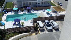 A rooftop swimming pool with lounge chairs and umbrellas, adjacent to a parking area with marked spaces. - Edgewater House - Ocean Front Units With Spectacular Views! (Rehoboth Beach)