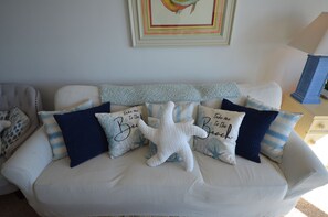 A beige sofa with multiple cushions, some with text, and a starfish-shaped pillow. - Edgewater House - Ocean Front Units With Spectacular Views! (Rehoboth Beach)