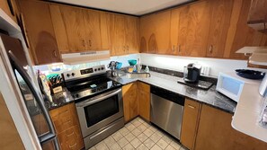 A kitchen with wooden cabinets, a stainless steel stove, a sink, and a microwave. - Edgewater House - Ocean Front Units With Spectacular Views! (Rehoboth Beach)