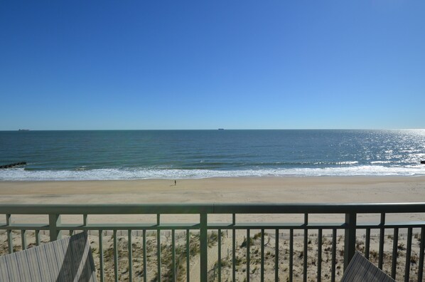 A beach view with a clear sky, a sandy shore, and a distant ship. - Edgewater House - Ocean Front Units With Spectacular Views! (Rehoboth Beach)