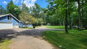 A residential property with a blue house, two garage doors, a driveway, and a well-maintained lawn. - Reggie's Northwoods Retreat (St Germain)
